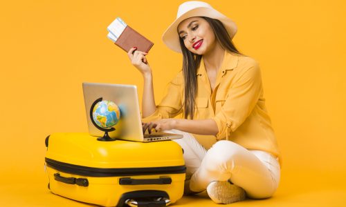 woman planning trip laptop while holding plane tickets passport